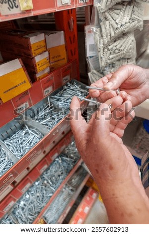 Carpenter comparing different screw sizes in a hardware store, making a selection for a construction or repair project