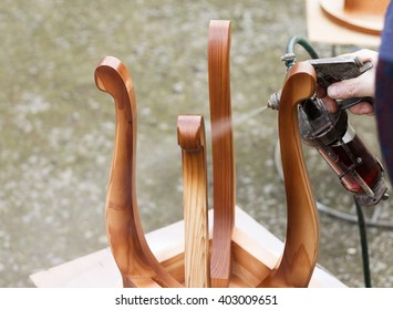 Carpenter Is Covering Stool By Lacquer. Furniture Varnishing Using Sprayer (pulverizer).