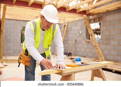 Carpenter Cutting House Roof Supports On Building Site