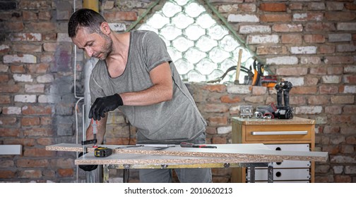 Carpenter doing wood work using clamping hand tool in his workshop.