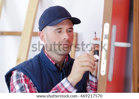 carpenter with doorlock during lock process installation into wood door