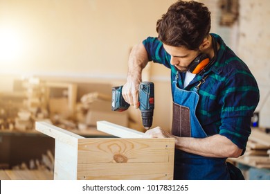 Carpenter drills a hole with an electrical drill - Shutterstock ID 1017831265