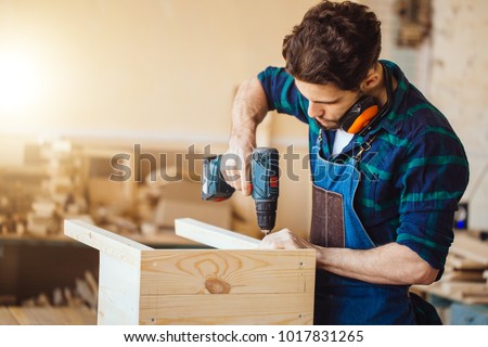 Carpenter drills a hole with an electrical drill