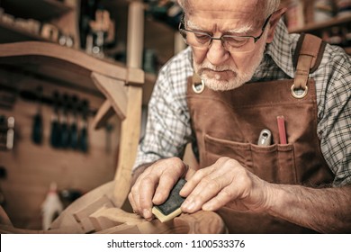 carpenter engaged in polishing an unfinished chair - Powered by Shutterstock