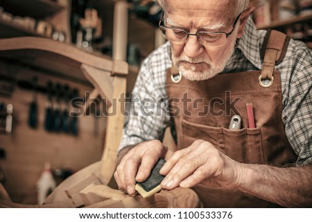 carpenter engaged in polishing an unfinished chair