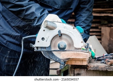 a carpenter is engaged in sawing boards with a circular saw at their summer cottage