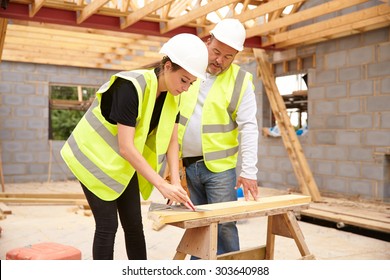 Carpenter With Female Apprentice Working On Building Site