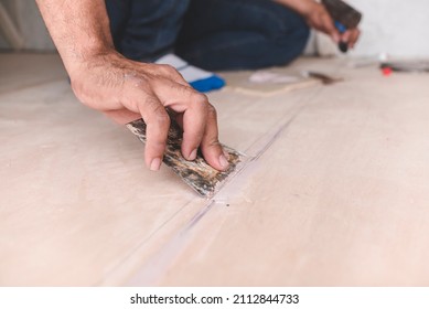 A carpenter filling gaps in wood floors. At the attic, home renovation, restoration or construction.
