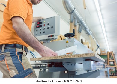 Carpenter in furniture factory pressing button on machine to start production 