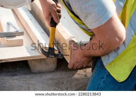 Carpenter hammering nail into the wood by hammer. Joiner with hammer and nail close-up