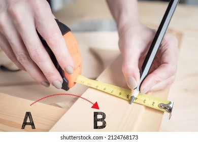 Carpenter hands with tape measure. Man draws a line with a tape measure. Roulette in hands of a carpenter close-up. He makes marks with a pencil. Letters A and B as symbols for solving problem