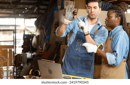 Carpenter and his assistant working together in a carpentry workshop - Powered by Shutterstock