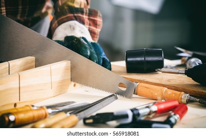 Carpenter holding a hand saw on the work bench - Powered by Shutterstock