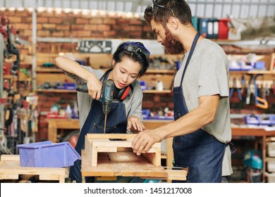 Carpenter holding wooden pieces when his coworker screwing wooden pieces together - Powered by Shutterstock