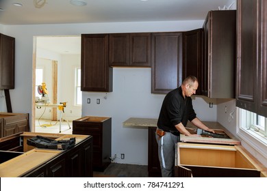 Carpenter Installing Cabinets And Counter Top In A Kitchen. And Partially Installed