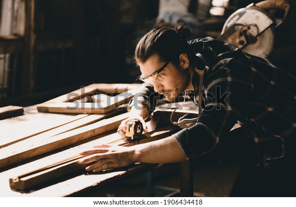 Carpenter man attend to\
making masterpiece woodworks handcrafted furniture fine measure in\
wood workshop.