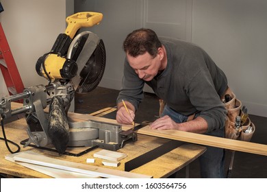 carpenter marking line on wood board during fixer upper home remodel construction project, with chop saw, ladder, level, leather tool belt, tradesmen, tradesman