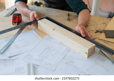 Carpenter measures wooden planks in the workshop. - Powered by Shutterstock