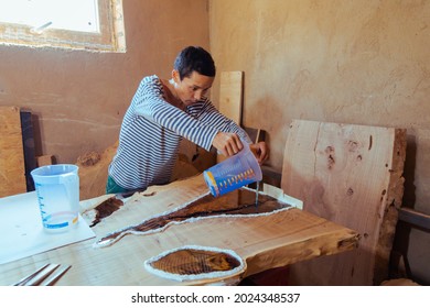 Carpenter Pouring Liquid Epoxy In A Wooden Table. Process Of Making A Craft Resin And Wood Table