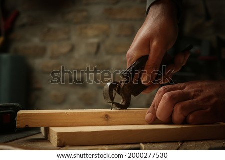Carpenter pulling the nail with carpenters pincers.	