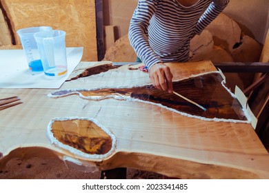 Carpenter Removing Air Bubbles From Epoxy Table. Process Of Making A Craft Resin And Wood Table