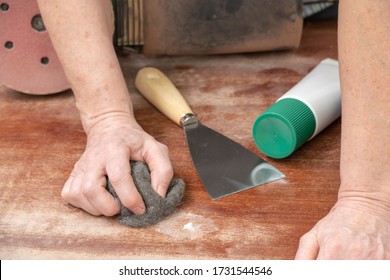 Carpenter Repairs A Defect In The Wood With Filler Putty