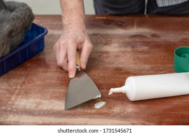 Carpenter Repairs A Defect In The Wood With Filler Putty