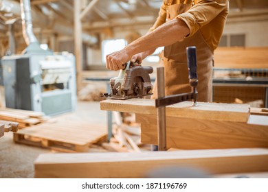 Carpenter sawing wooden bars with cordless electric saw at the joiner's workshop - Powered by Shutterstock