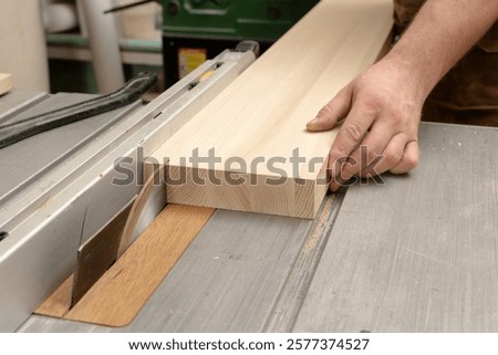 A carpenter saws a thin plank from an ash board