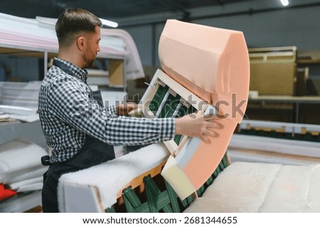 Carpenter skillfully assembling a stylish sofa using foam and wood in a bustling furniture factory, showcasing expert craftsmanship and quality