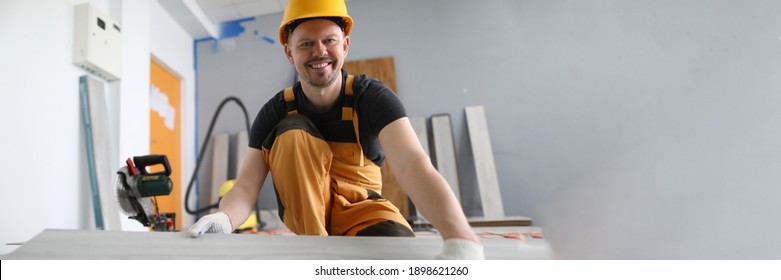 A carpenter smiles while holding a laminate. Laying technology with Click lock. Features of sawing laminate - Shutterstock ID 1898621260
