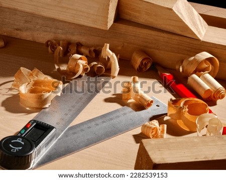 Carpenter table with small timbers, wood shavings, digital angle finder and a pencil, close up