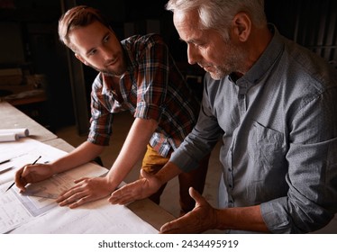 Carpenter, team and men with blueprint for discussion of construction project or father teaching son. Engineer, apprentice and senior mentor with design, drawing and planning for training at workshop - Powered by Shutterstock