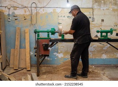 Carpenter turning wood on a lathe in workshop. Person carving with chisel turning blanks on a lathe