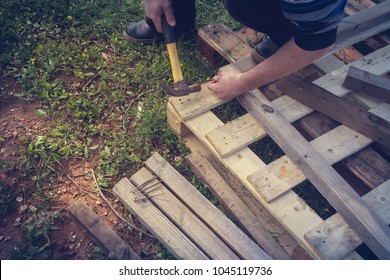 A Carpenter Is Upcycling A Wooden Pallet Making A Construction With A Hammer