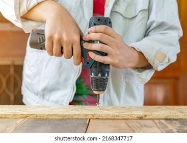 The Carpenter Use Two Hands Catch Cordless Screwdriver Tighten Screw On Wood Plank. The Carpenter Workshop.