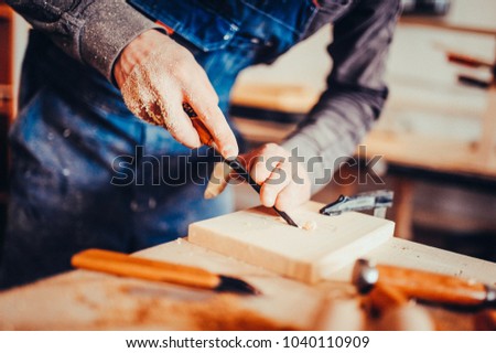 The carpenter uses a chisel for carving. Carving view. Toned image.