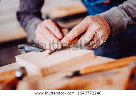 The carpenter uses a chisel for carving. Carving view. Toned image. from the front view