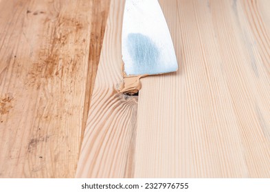 Carpenter uses putty to smooth out the knots in a wooden board. Recovery background. - Shutterstock ID 2327976755