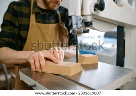 Carpenter using band saw to cut plywood, closeup shot with selective focus