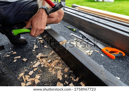 Carpenter using a chisel and hammer to create a mortise joint in a wooden beam