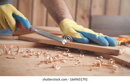 Carpenter using chisel into wooden plank.