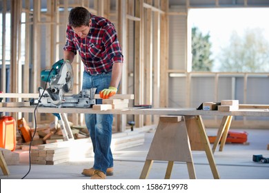 Carpenter Using Circular Power Saw To Cut Wood On Indoor Building Construction Site