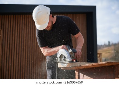 Carpenter Using Circular Saw For Cutting Wooden Plank. Man Worker Building Wooden Frame House. Carpentry Concept.