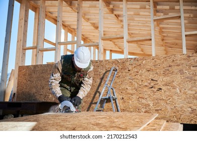 Carpenter using circular saw for cutting wooden OSB board. Man worker building wooden frame house on pile foundation. Carpentry concept. - Shutterstock ID 2170212543