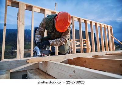 Carpenter using circular saw for cutting wooden plank. Man worker building wooden frame house. Carpentry concept. - Powered by Shutterstock