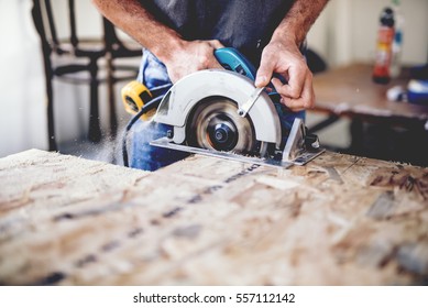 Carpinteiro usando serra circular para cortar tábuas de madeira. Detalhes de construção do trabalhador masculino ou homem útil com ferramentas elétricas