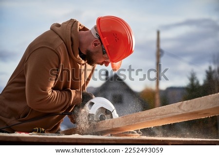 Carpenter using circular saw for cutting wooden plank. Man worker building wooden frame house. Carpentry concept.