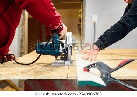 Carpenter using circular saw for cutting wooden OSB board. 