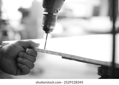 Carpenter is using a drill press to make a hole in a wood plank in his workshop. - black n white -  - Powered by Shutterstock